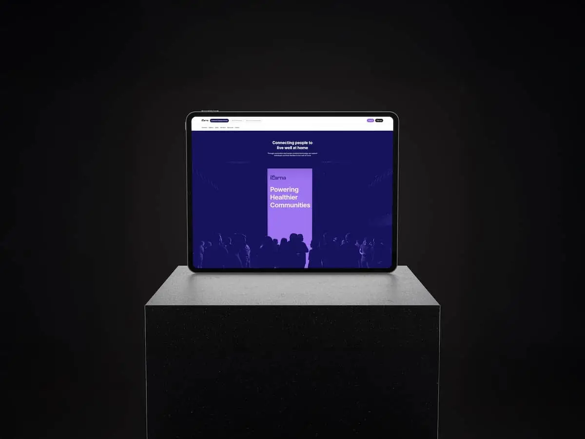 Tablet on a pedestal showing a purple conference slide reading 'Powering Healthier Communities' on a dark background.