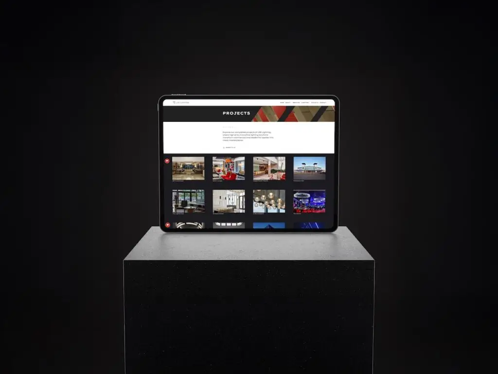 Tablet on a pedestal displaying a grid of project thumbnails under a 'PROJECTS' header on a dark screen background.